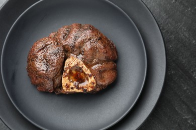 Piece of tasty grilled beef meat on black table, top view