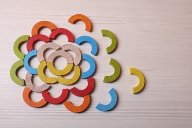 Photo of Colorful wooden pieces of educational toy on light table, flat lay and space for text. Motor skills development