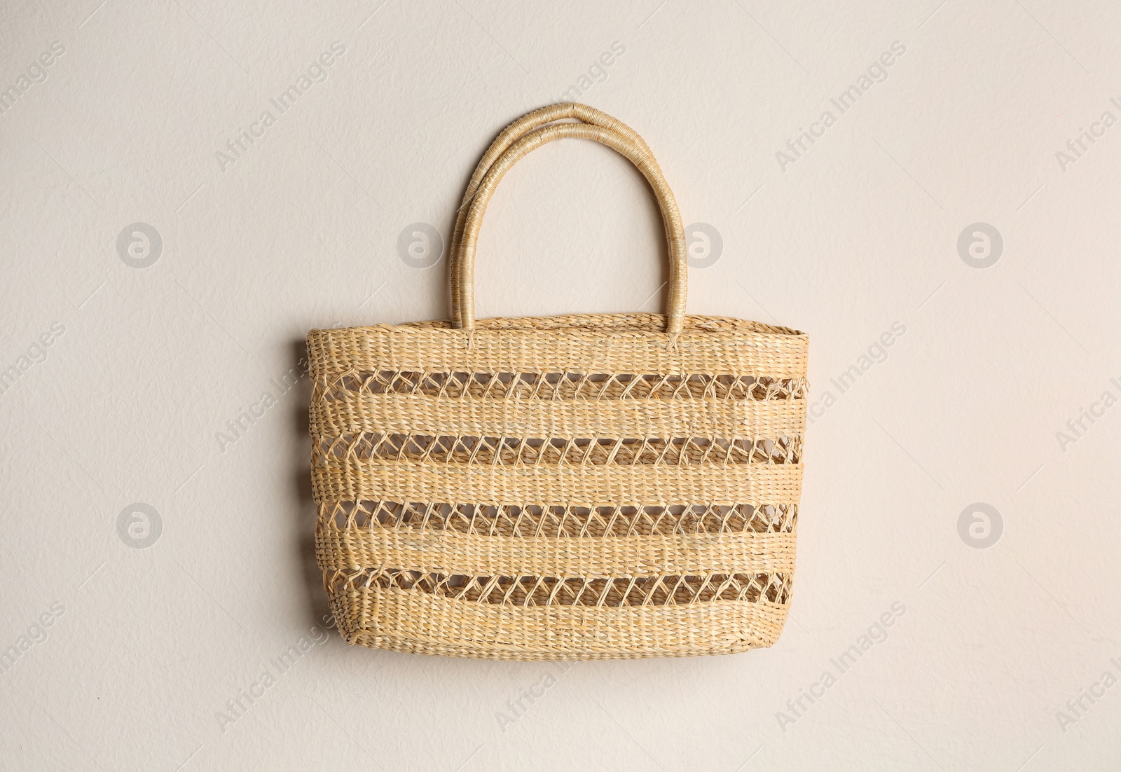 Photo of Elegant woman's straw bag on beige background, top view