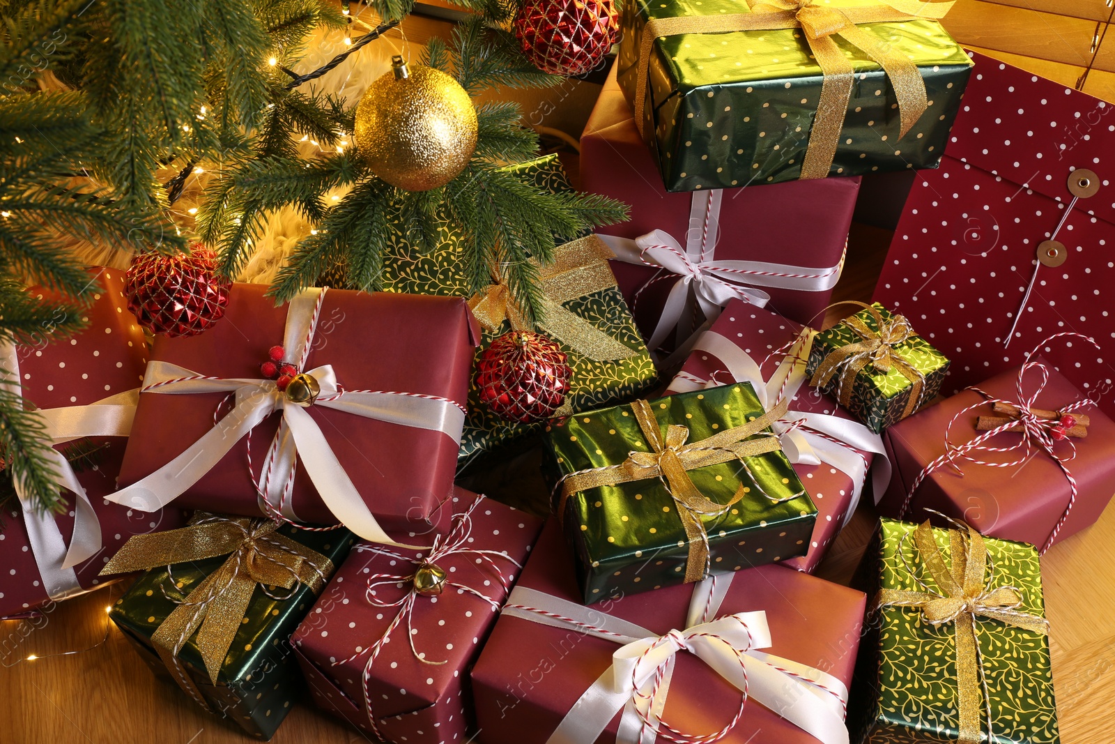 Photo of Pile of gift boxes near Christmas tree on floor