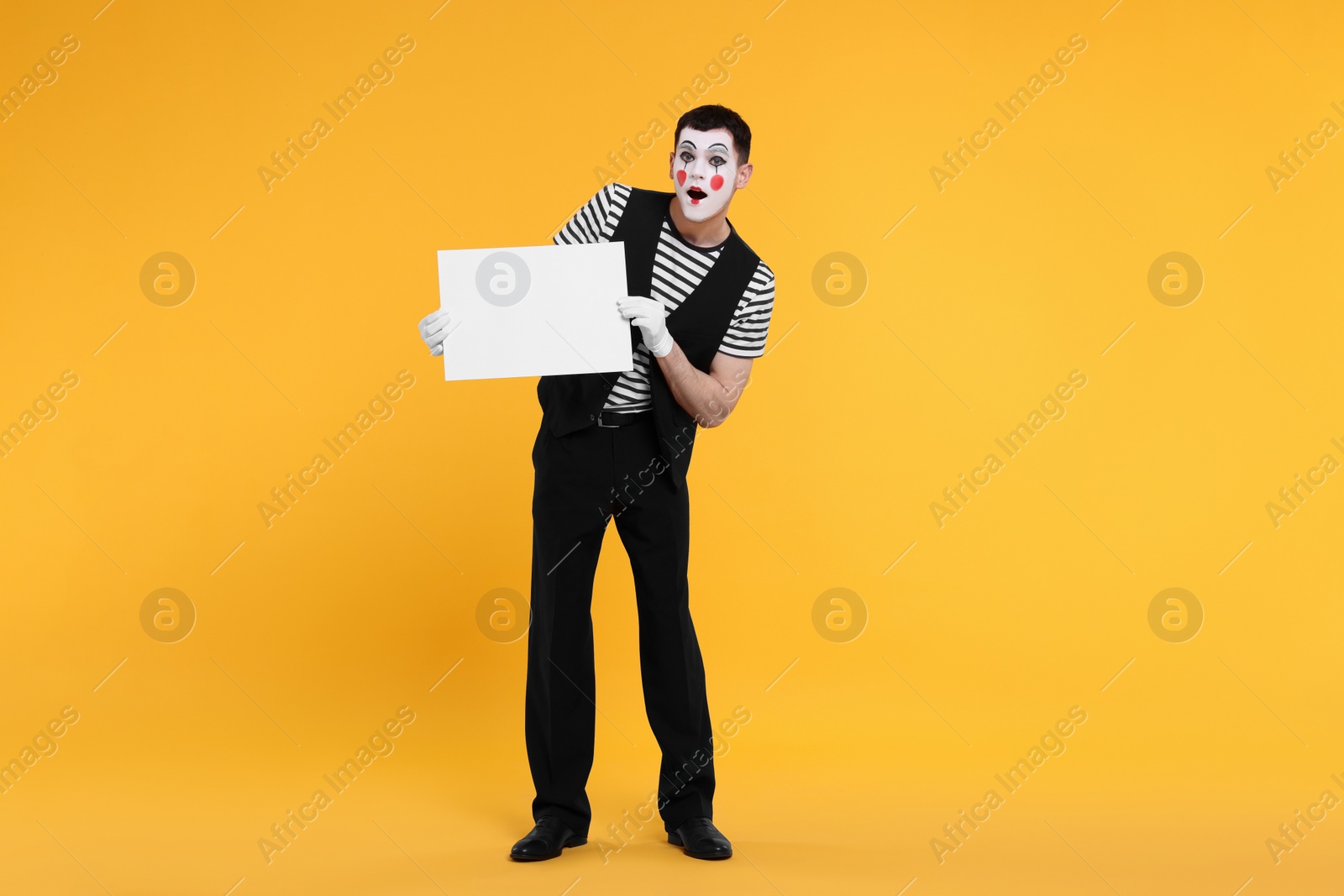 Photo of Funny mime artist with blank sign on orange background. Space for text