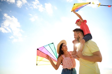 Photo of Happy parents and their child playing with kites on sunny day. Spending time in nature