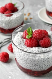 Photo of Delicious chia pudding with raspberries and mint on light marble table, closeup