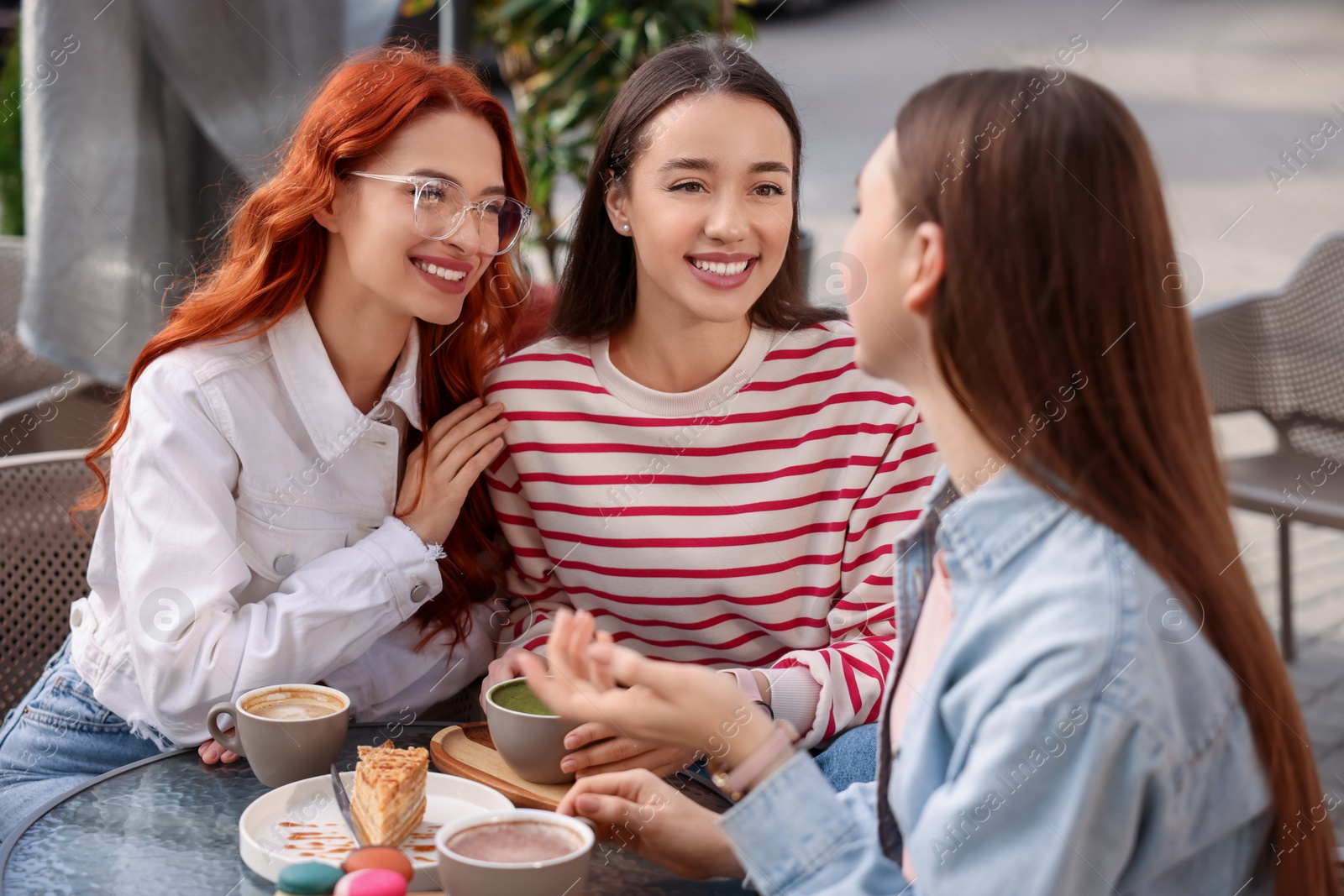 Photo of Happy friends spending time together in outdoor cafe