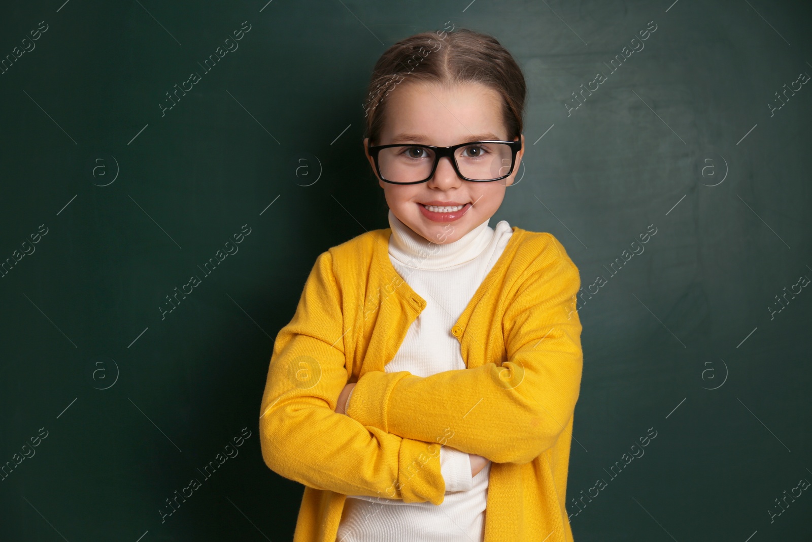 Photo of Cute little child wearing glasses near chalkboard. First time at school