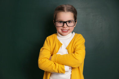 Cute little child wearing glasses near chalkboard. First time at school