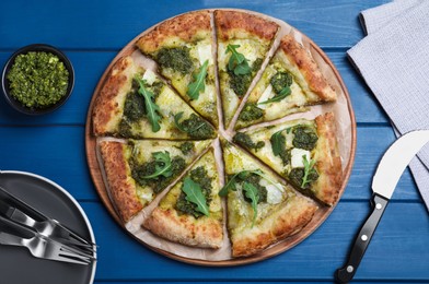 Delicious pizza with pesto, cheese and arugula served on blue wooden table, flat lay