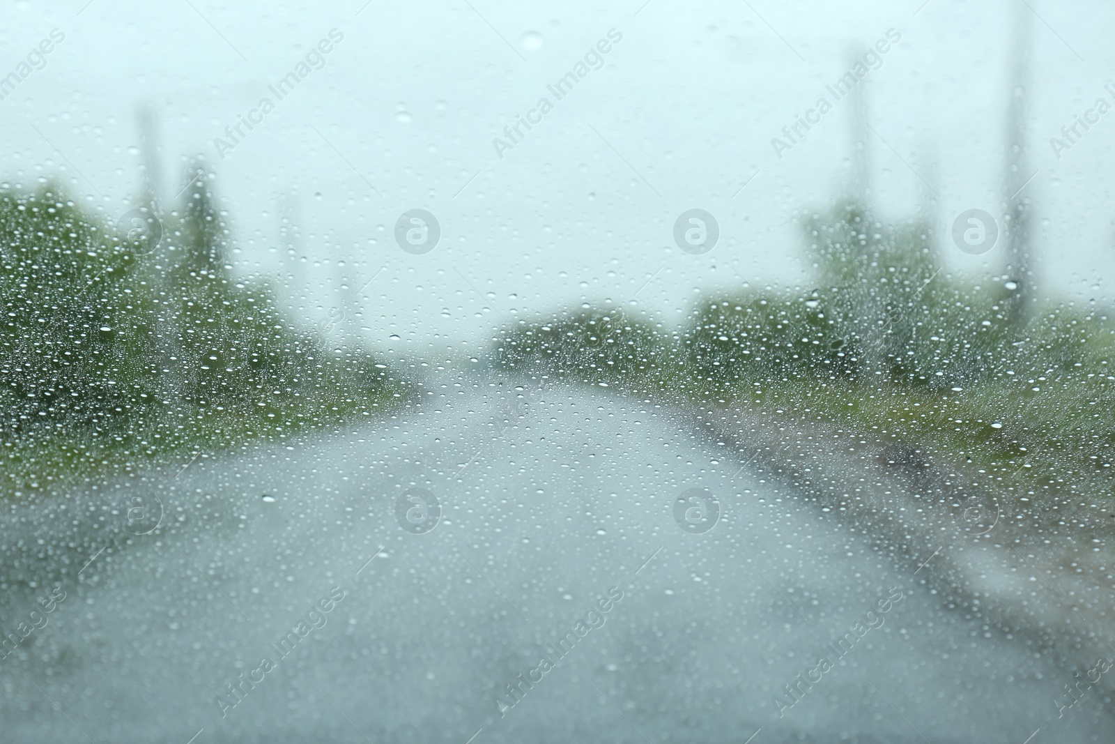 Photo of Blurred view of country road through wet car window. Rainy weather