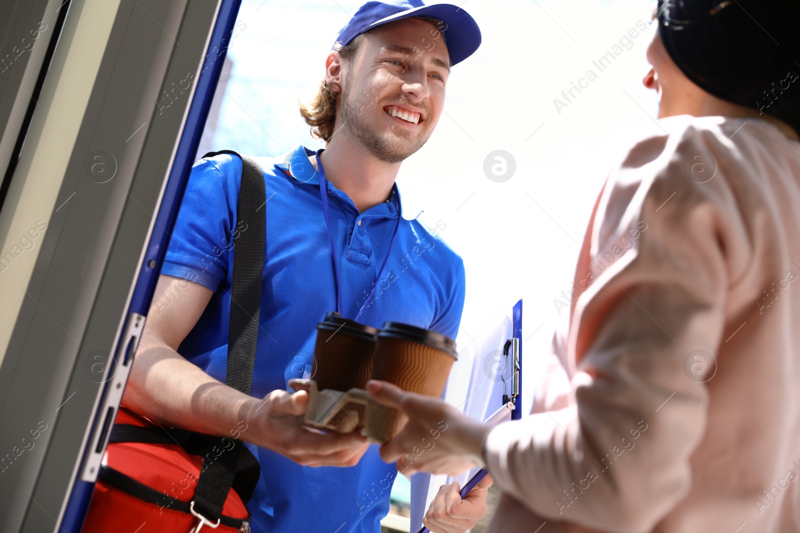 Photo of Woman receiving order from courier at door. Food delivery service