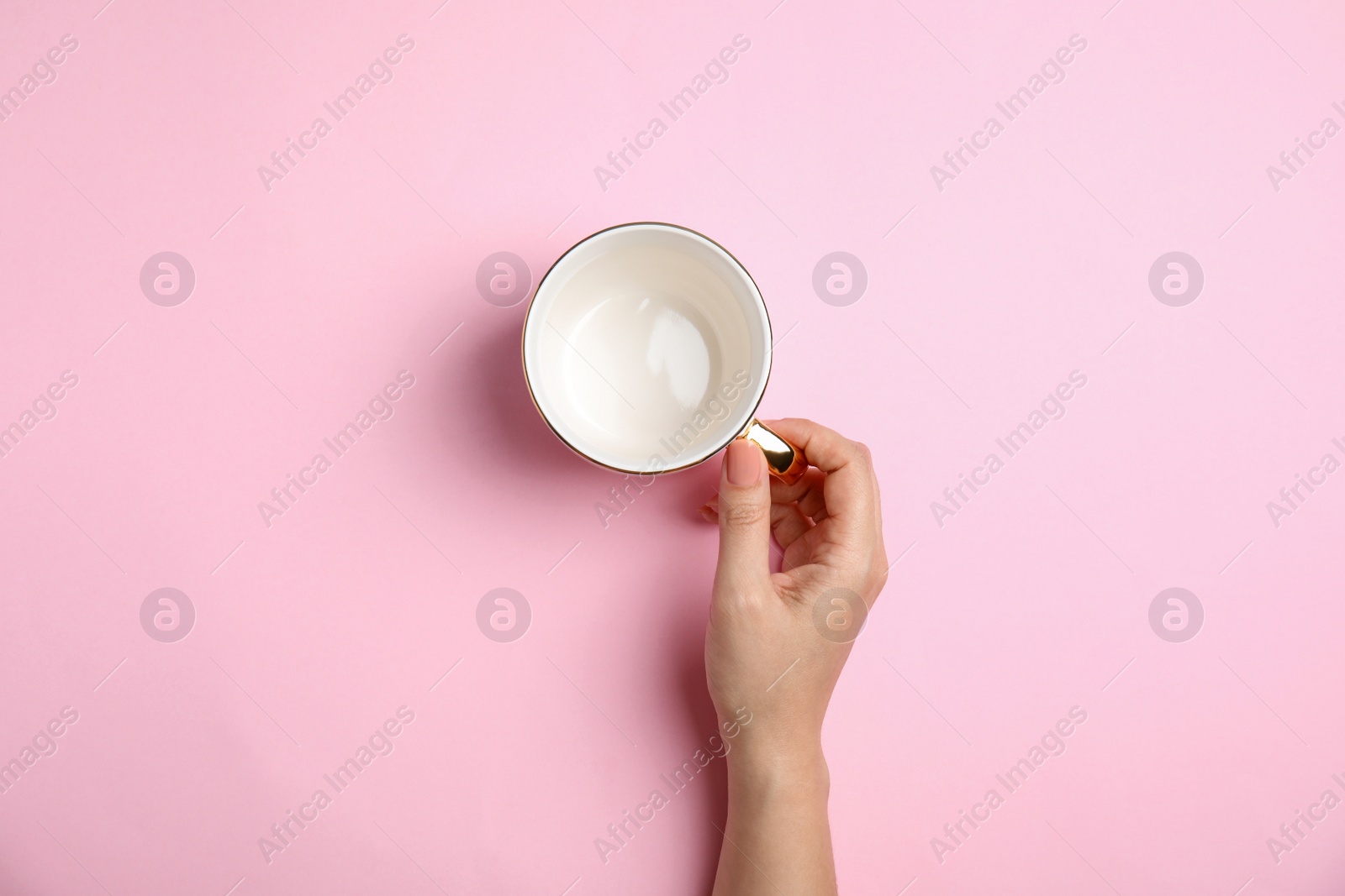 Photo of Woman with empty cup on light pink background, top view