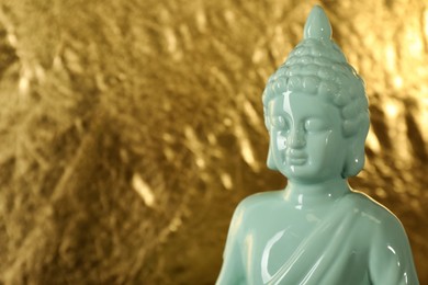 Photo of Buddha statue on golden background, closeup. Space for text