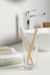Photo of Bamboo toothbrushes and towels on white countertop in bathroom
