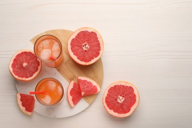Photo of Tasty freshly made grapefruit juice and fruits on white wooden table, top view. Space for text