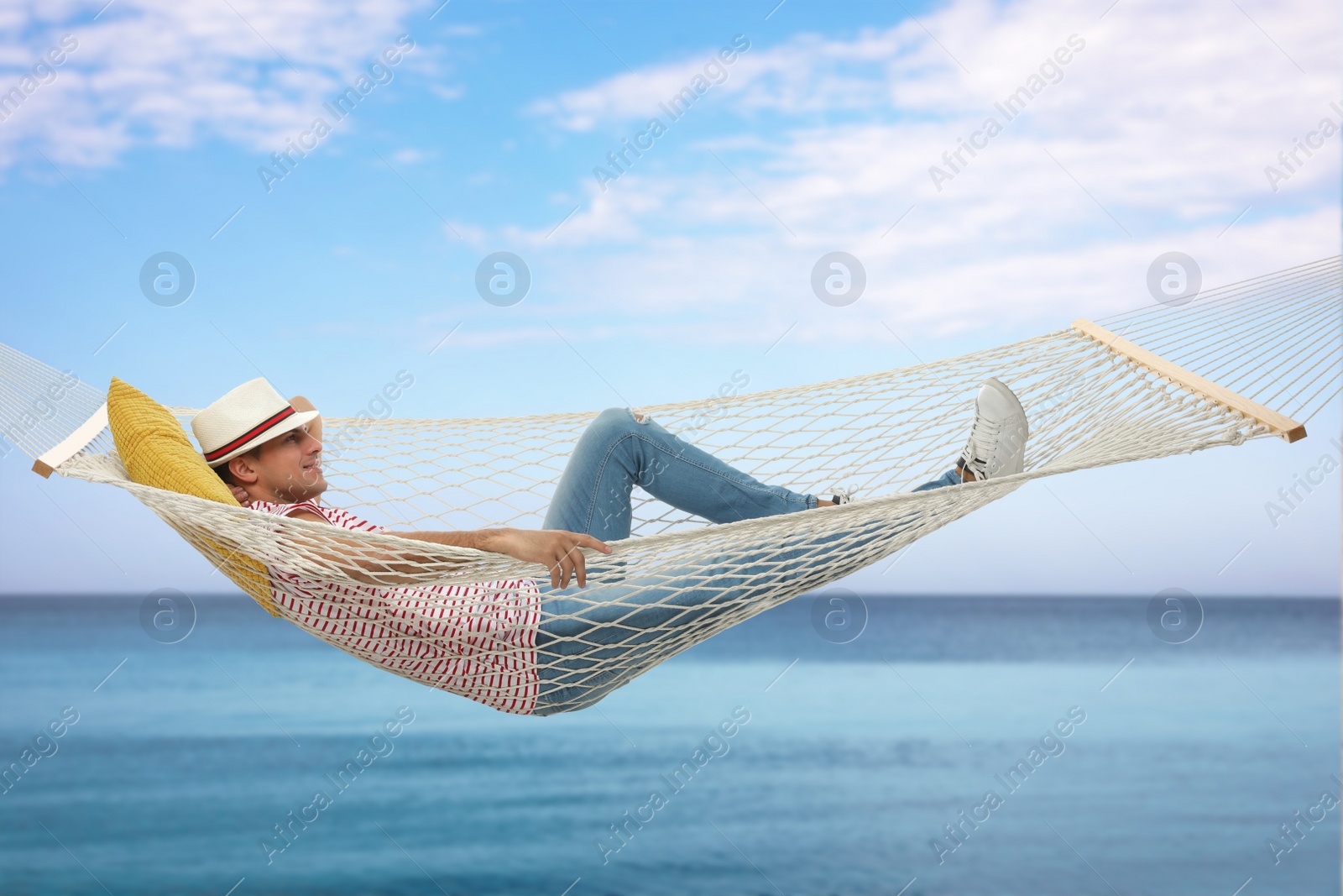 Image of Man resting in hammock near sea on sunny day 
