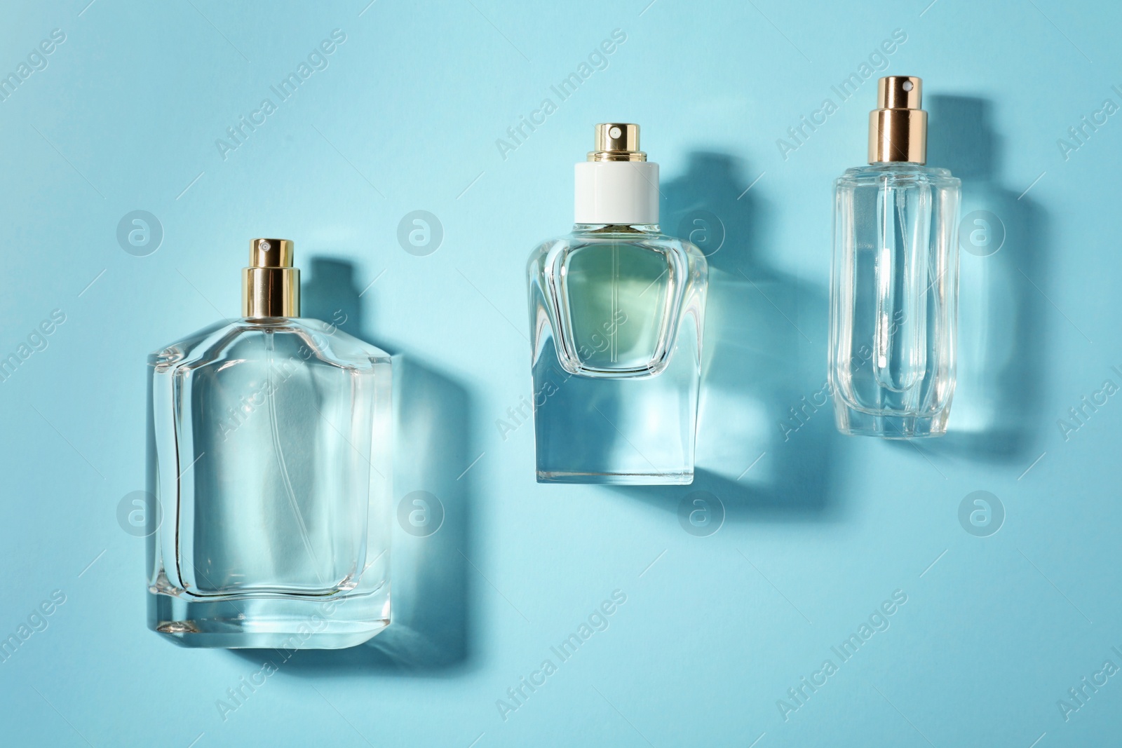 Photo of Bottles of perfume on color background, top view