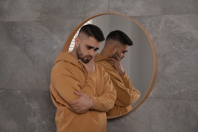 Photo of Sad young man near mirror at home