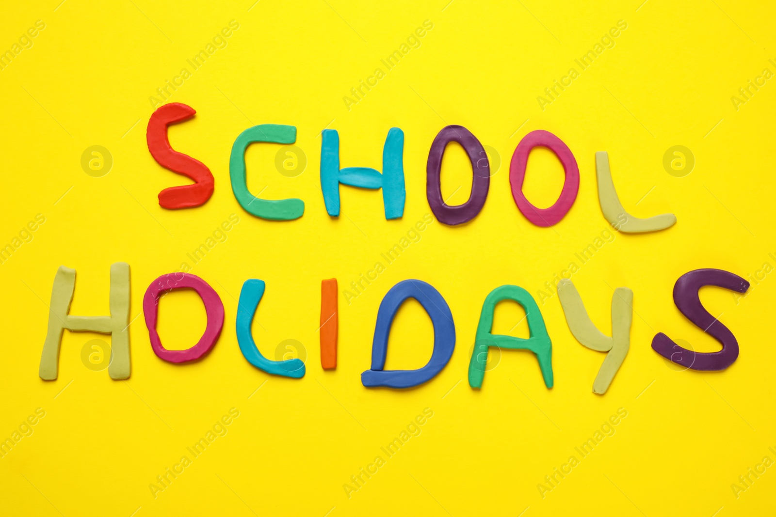 Photo of Phrase School Holidays made of modeling clay on yellow background, top view