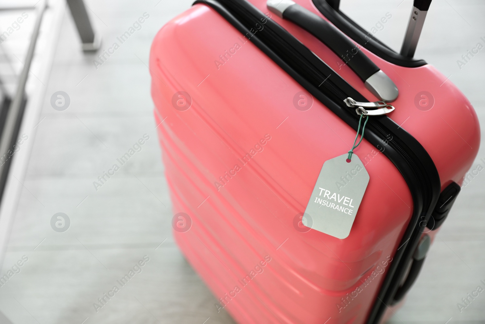 Photo of Stylish suitcase with travel insurance label on blurred background, closeup. Space for text