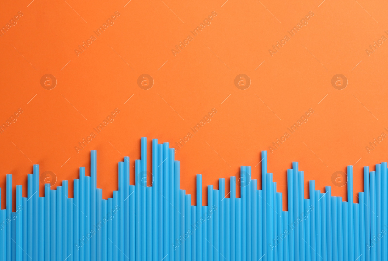 Photo of Heap of blue plastic drinking straws on orange background, flat lay. Space for text