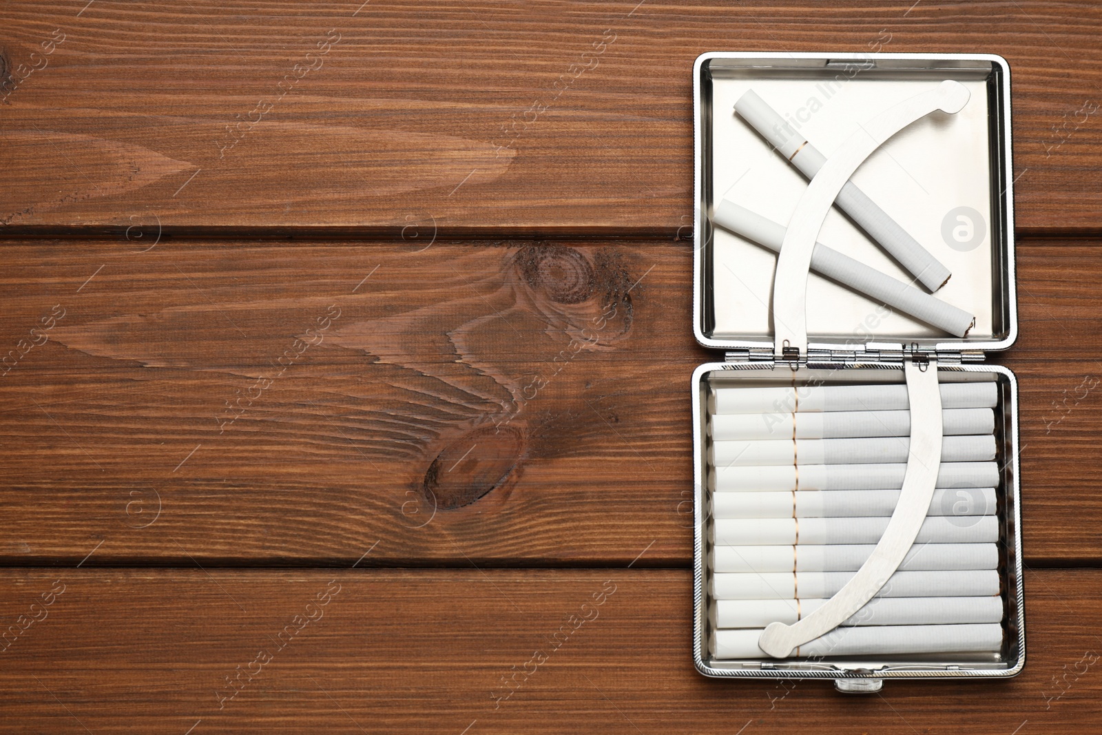 Photo of Stylish case with cigarettes on wooden table, top view. Space for text