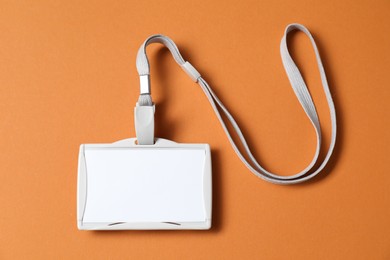 Photo of Blank badge with string on orange background, top view