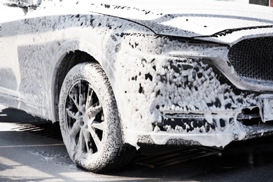 Modern automobile covered with foam at car wash