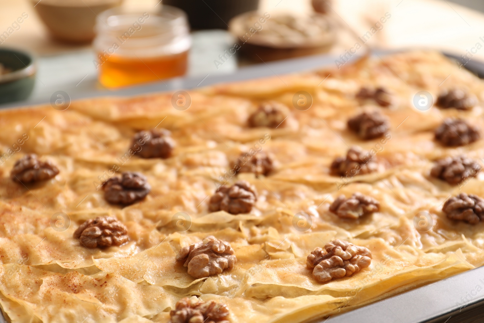 Photo of Delicious baklava with walnuts in baking pan on table, closeup