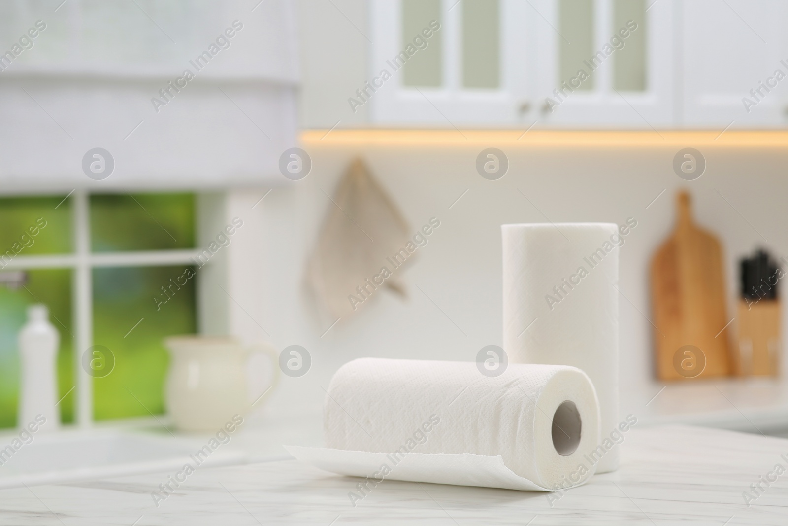 Photo of Rolls of paper towels on white marble table in kitchen. Space for text