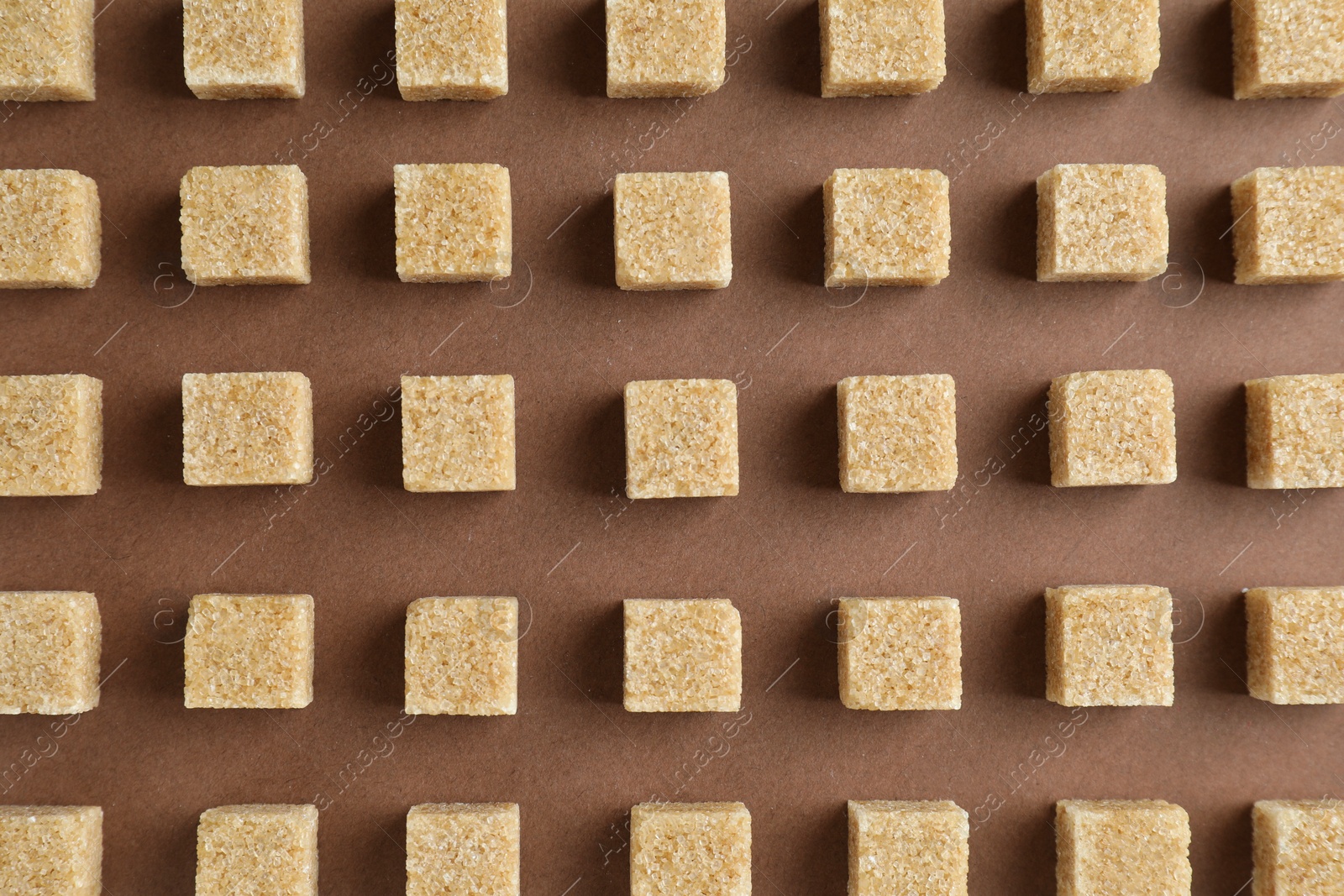 Photo of Brown sugar cubes on color background, top view