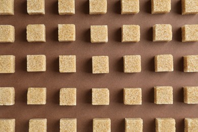 Photo of Brown sugar cubes on color background, top view