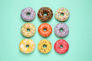 Delicious glazed donuts on turquoise background, flat lay