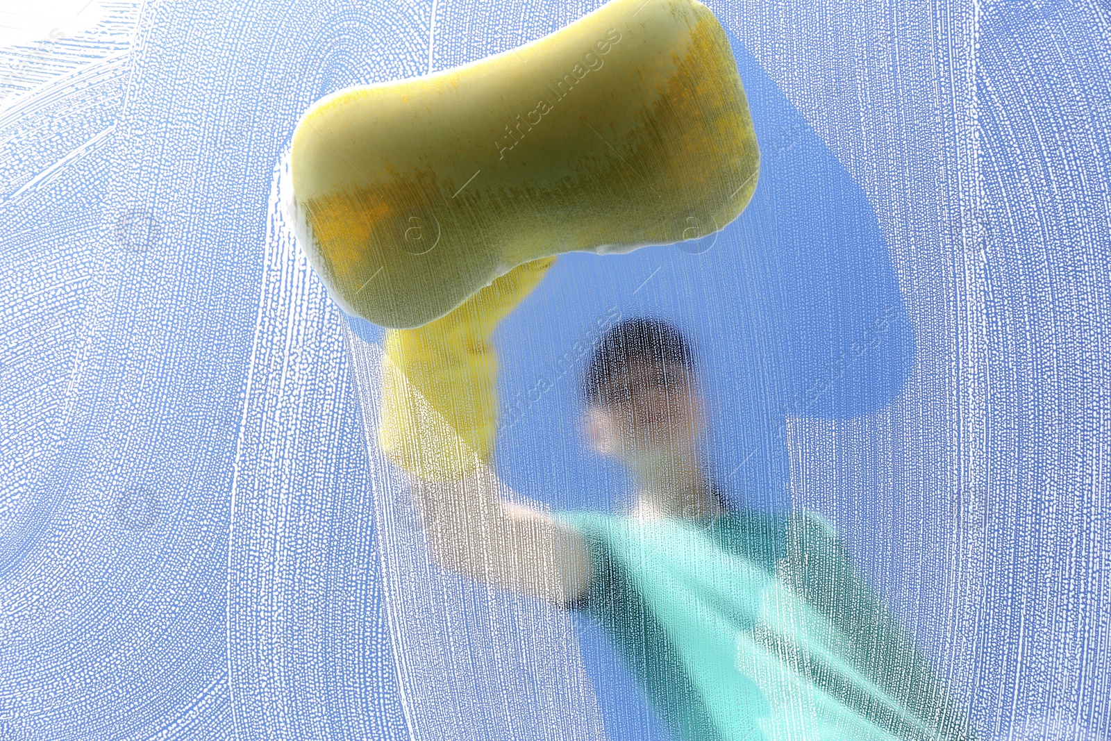 Photo of Woman cleaning glass with sponge on sunny day