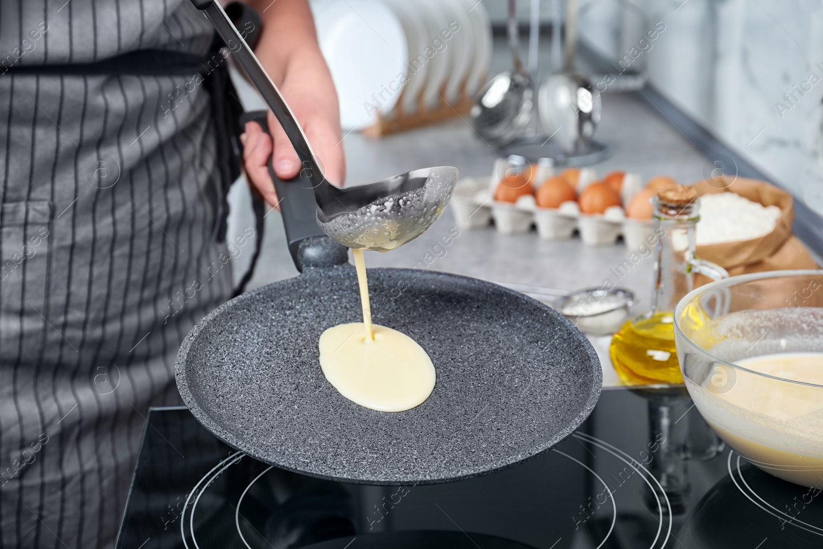 Photo of Woman cooking delicious thin pancakes on induction stove, closeup