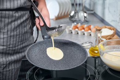 Photo of Woman cooking delicious thin pancakes on induction stove, closeup