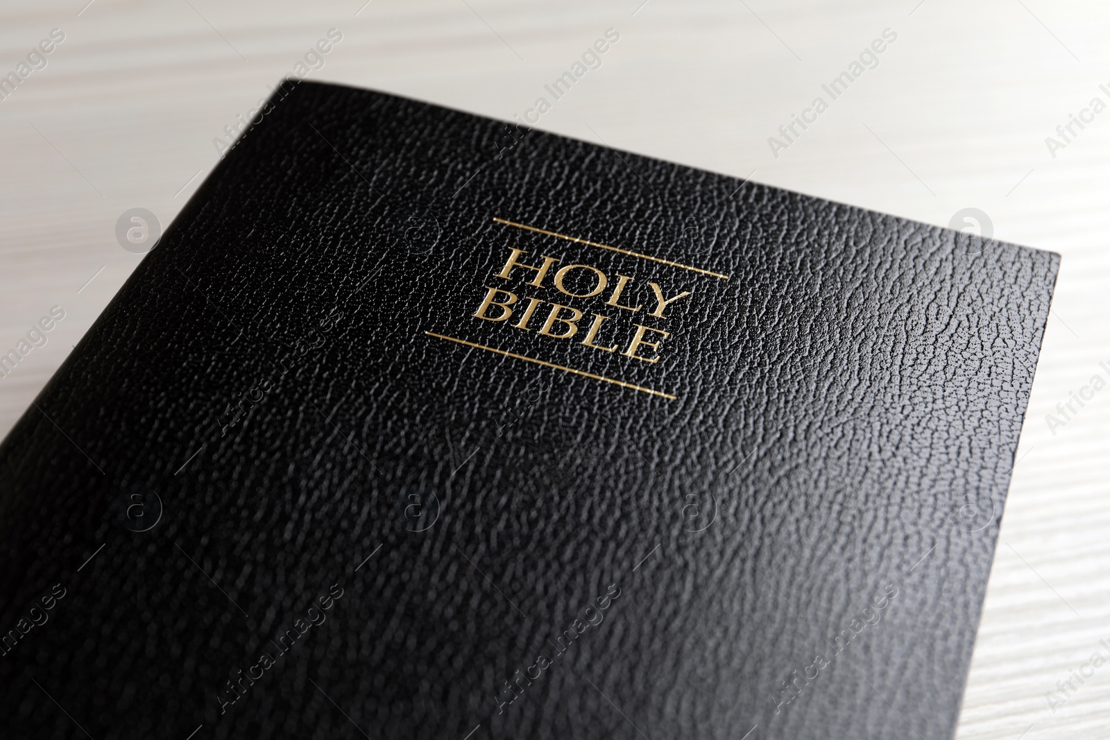 Photo of Holy Bible on white wooden table, closeup