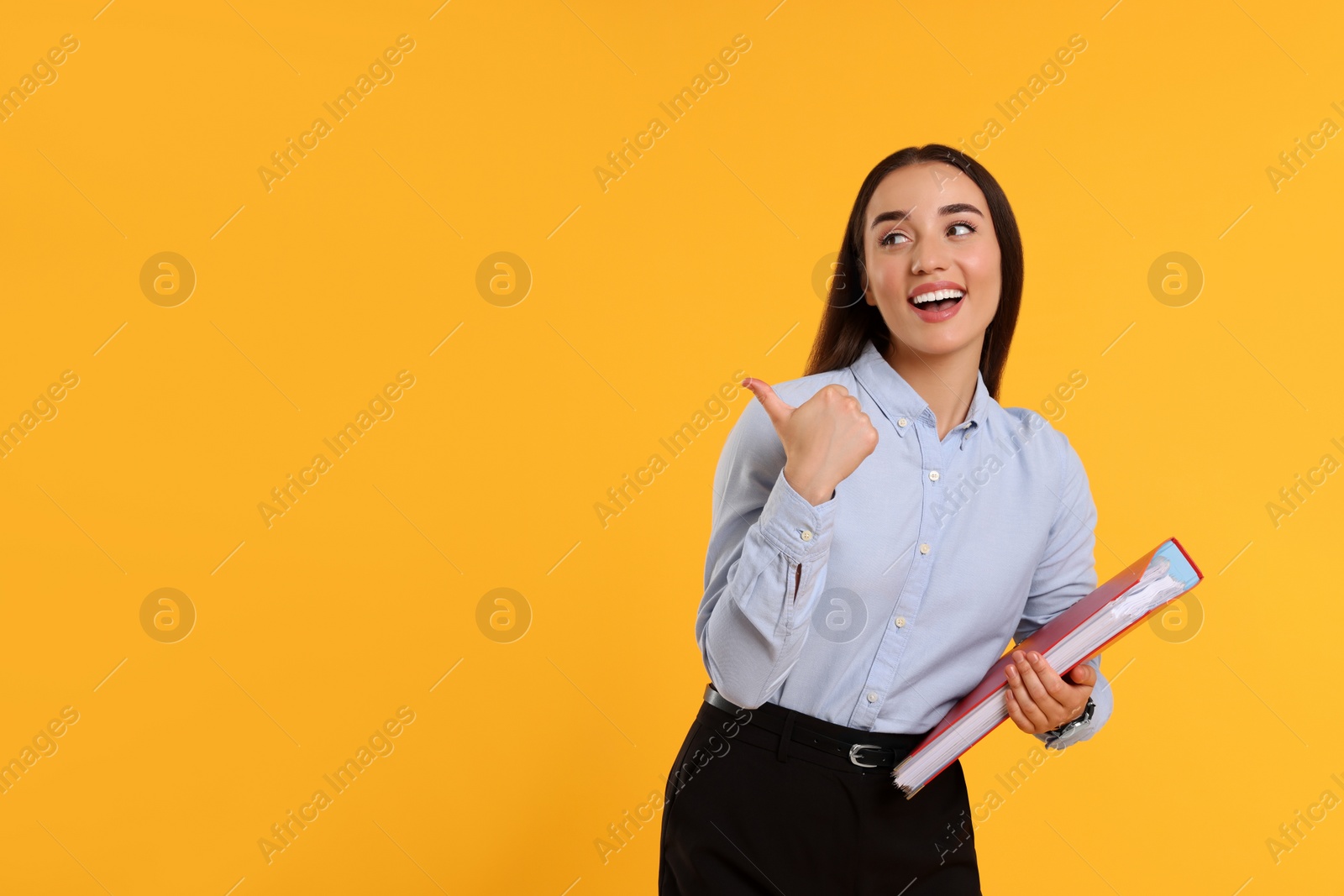 Photo of Happy woman with folder on orange background, space for text