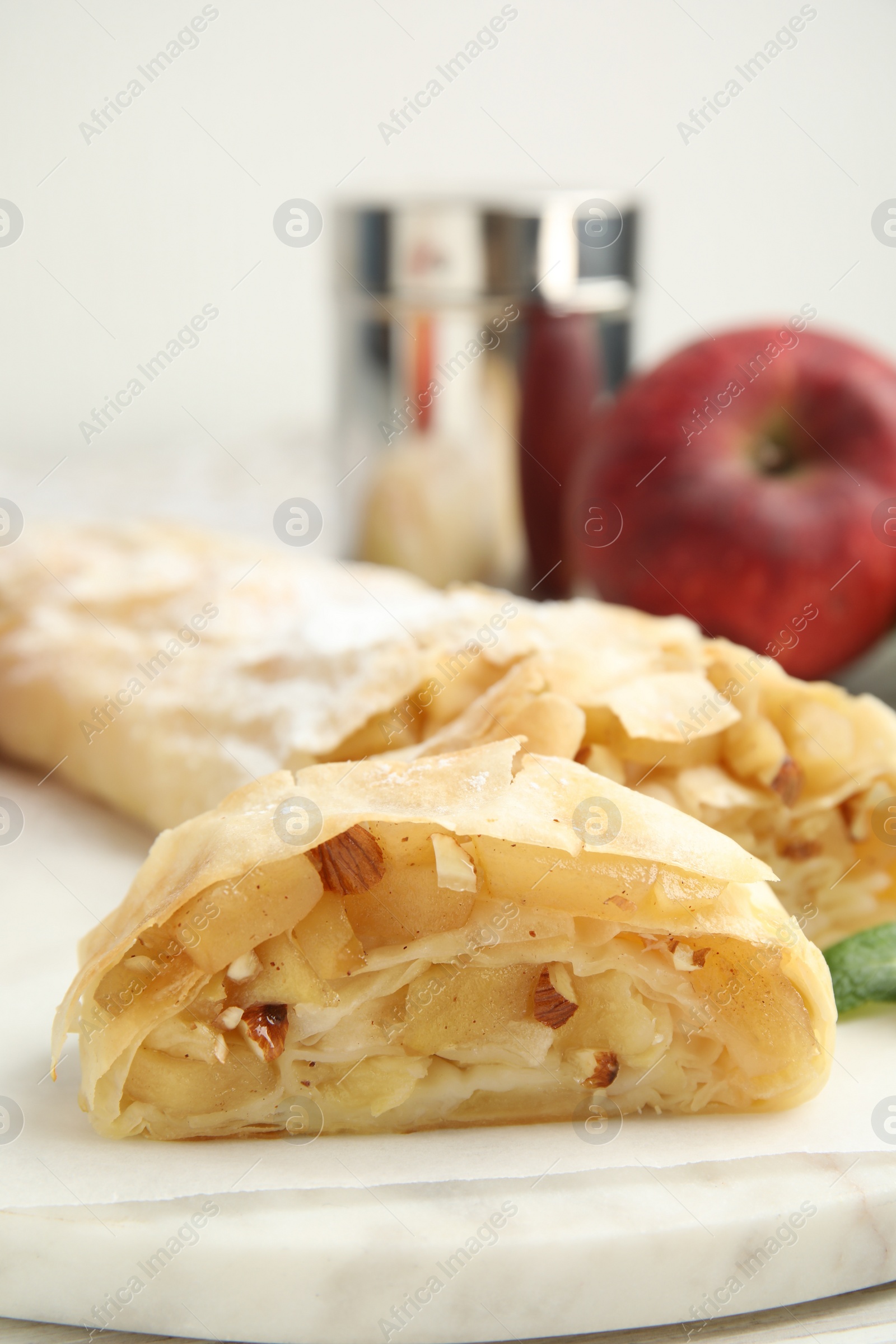 Photo of Delicious apple strudel with almonds on white board, closeup