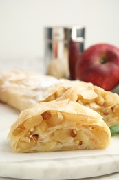 Delicious apple strudel with almonds on white board, closeup