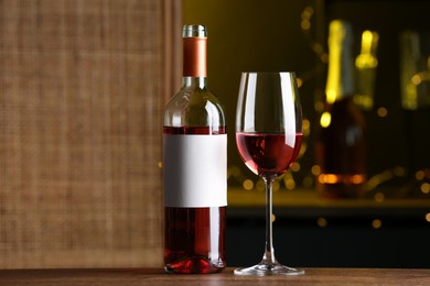 Bottle and glass of delicious rose wine on wooden table in bar