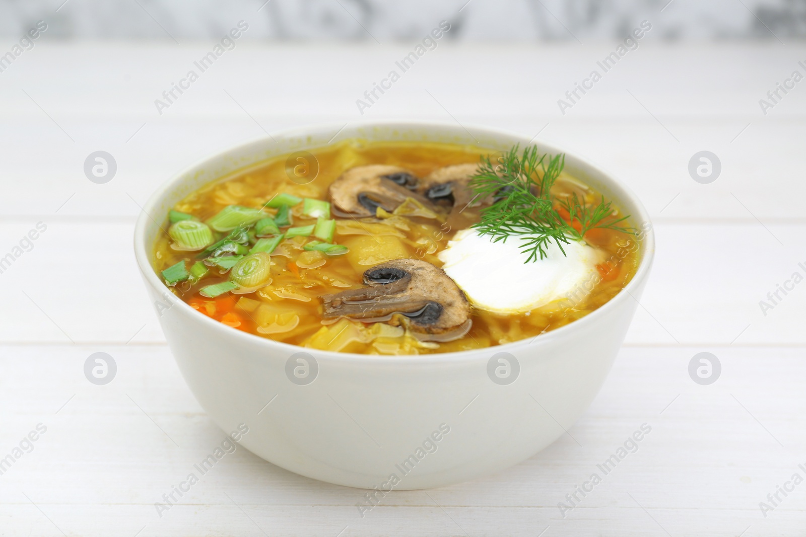 Photo of Delicious sauerkraut soup with mushrooms, green onion, dill and sour cream on white table