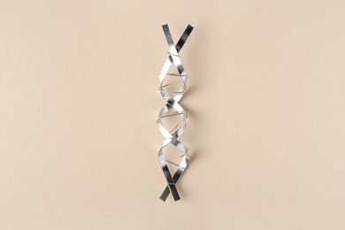 DNA molecular chain model made of metal on beige background, top view