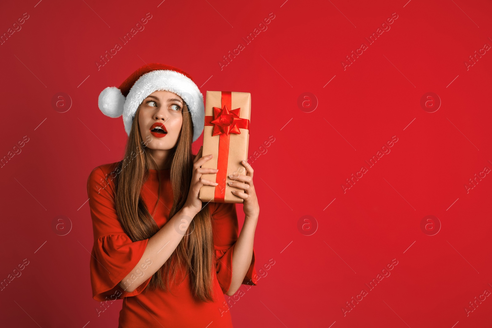 Photo of Young beautiful woman in Santa hat with gift box on color background. Christmas celebration