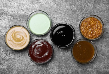 Photo of Many different sauces on grey table, flat lay