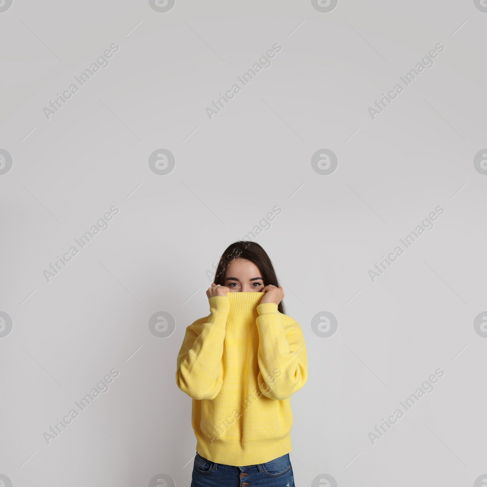 Photo of Beautiful young woman wearing yellow warm sweater on white background. Space for text