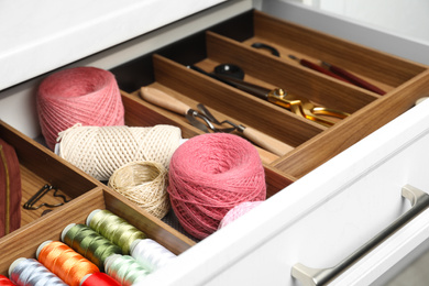 Photo of Sewing accessories in open desk drawer indoors, closeup