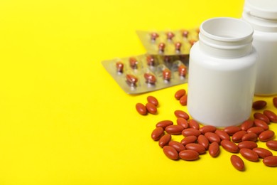 Photo of Bottles with pills on yellow background, space for text. Anemia treatment