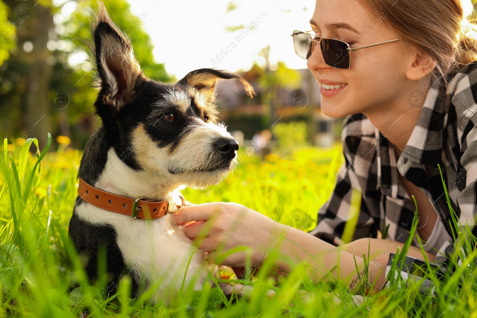 Photo of Teenage girl with her cute dog resting on green grass in park