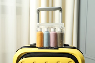Photo of Cosmetic travel kit. Plastic bag with small containers of personal care products on suitcase indoors