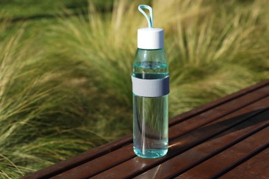 Glass bottle with water on wooden surface outdoors