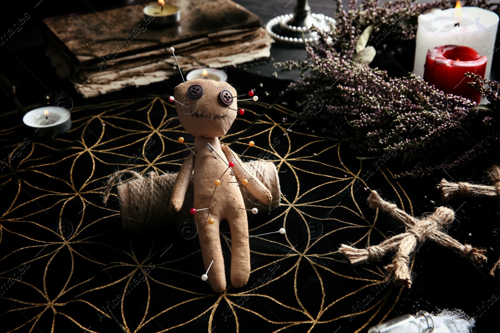 Photo of Voodoo doll pierced with pins on table. Curse ceremony